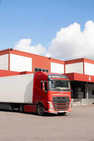 A red truck is parked at a warehouse, loaded with goodsのeditorial素材