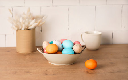 preparation for Easter holiday. fresh colored chicken eggs lie in a deep bowl on the table in the...