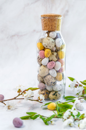 A Glass Bottle Filled With Easter Eggs And Flowers