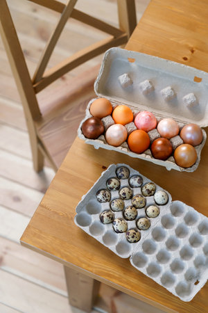 Easter chicken eggs and quail eggs in an egg box lie on the edge of the table