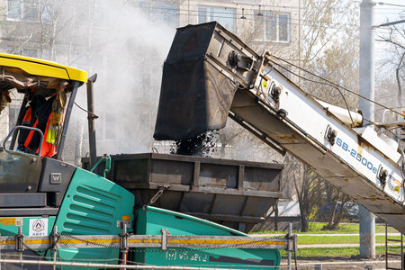 Construction equipment is active, pouring asphalt, during road construction work