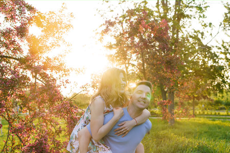 A happy couple embrace a blooming orchard at sunsetの写真素材