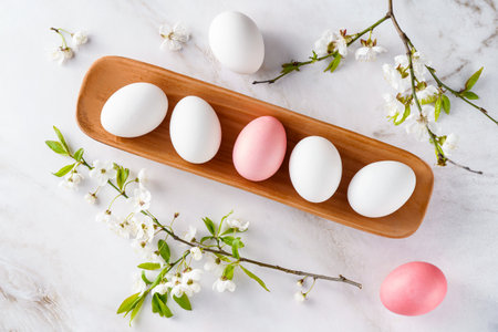Chicken eggs in plate on framed by branches of flowering apple tree