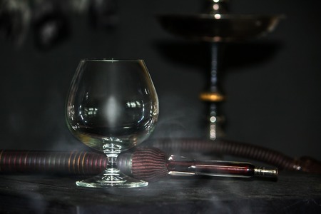 Heavy hookah smoke under a brandy glass on a gray background, hookah tubeの写真素材