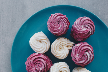 White mango and pink blueberry marshmallows or zephyr with sugar powder on a blue plate. Homemade sweet.の写真素材