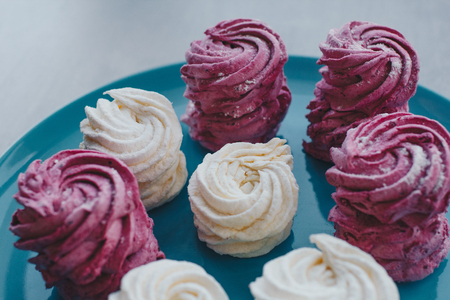 White mango and pink blueberry marshmallows or zephyr with sugar powder on a blue plate. Homemade sweet.の写真素材