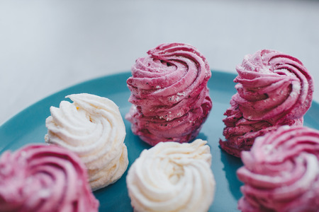 White mango and pink blueberry marshmallows or zephyr with sugar powder on a blue plate. Homemade sweet.の写真素材