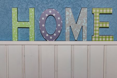 Sign saying 'Home' on a blue and white wallの写真素材