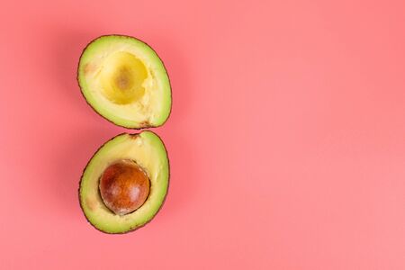 Two halves of avocado with stone on pink background. Healthy food concept.の写真素材