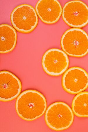 Background of sliced ripe oranges on a pink background vertical. Conceptual creative approachの写真素材
