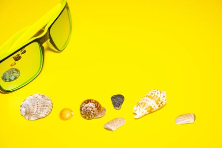 Sun glasses sea shells bright yellow background. Concept summer holidays travel. Top viewの写真素材
