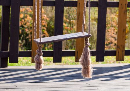Swing on the playground close-up on a background of a wooden fence.の写真素材