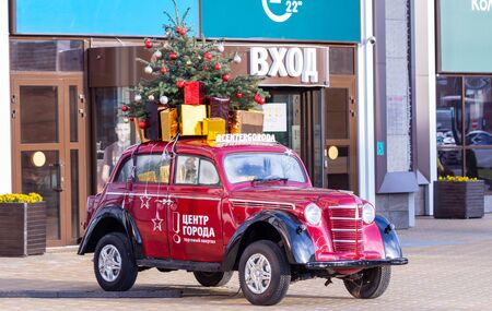 Russia, Krasnodar. December 12, 20019. Near the entrance to the mall there is a red car on it a New Year tree. By car the text is written: City Center. Shopping quarter.のeditorial素材