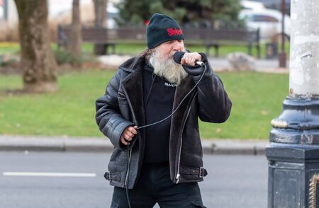An elderly man with a microphone sings on the street.のeditorial素材