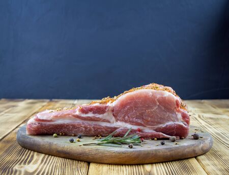 One piece pork tenderloin on a wooden board with fresh vegetables and spices in a rustic style. Raw pork meat.の写真素材