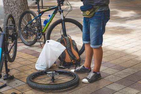 Bicycle repair. A man repairs a bicycle wheel in the street.の写真素材