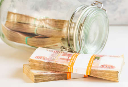 Russian ruble. money in a glass jar. On a white background close-up of a bundle of banknotes. Saving...