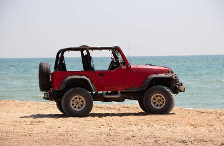 Russia. Krasnodar July 1, 2020. Red car on the sandy seashore. Summer vacation at the sea.