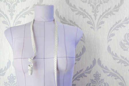 Lilac tailors mannequin for sewing clothes and tape measure.