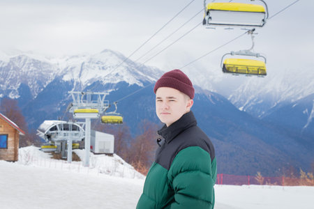 Ski resort. The young man admires nature, stands against the background of the mountains.