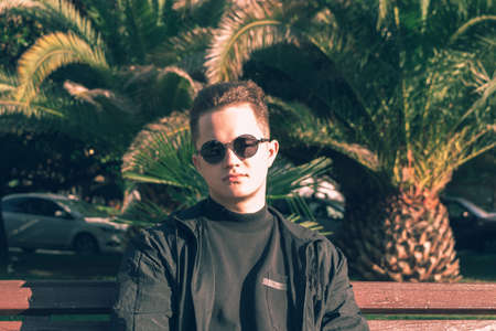Portrait of a young guy on a background of palm trees.の写真素材