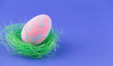 Pink Easter egg on a blue background. Bright Easter composition. Place for text.の写真素材