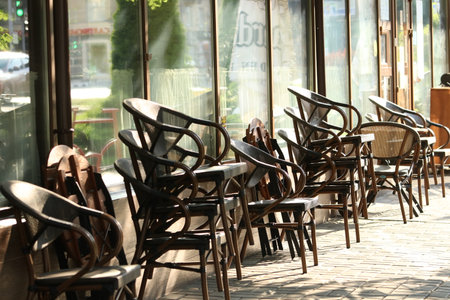Sidewalk cafe yet unopened with a stacked chairs and beautiful light reflections in the windows