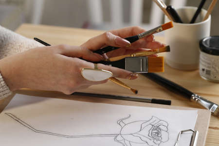 Female concept artist holding brushes by a pencil flower design