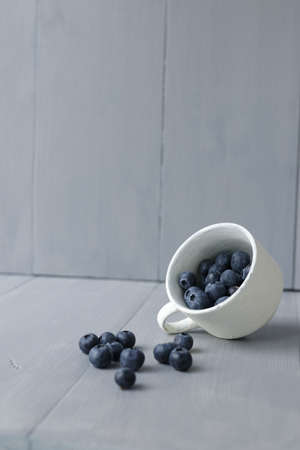 White cup with blueberries on gray tableの写真素材