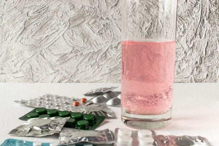 Soluble tablet in a glass of water. Tablets in packing on a light background. Pills.の写真素材
