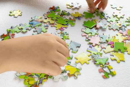 child plays puzzles, puzzles with baby handles, Children's hand with colored toy puzzlesの写真素材