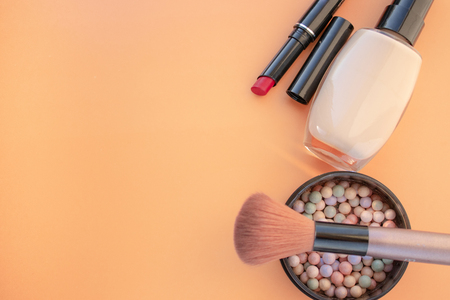 Cosmetic accessories. Brush, blush, lipstick, cream on a yellow, cream background. With empty space on the left. View from aboveの写真素材