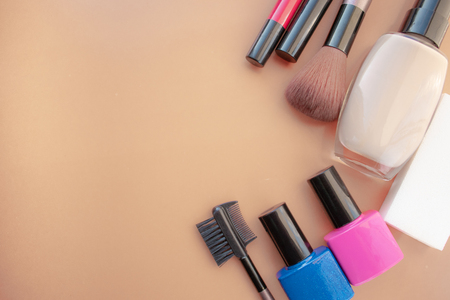 Cosmetic accessories. Brush, blush, lipstick, cream, nail polish on a yellow, cream background. With empty space below. View from aboveの写真素材