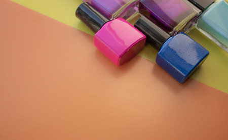 Bottles of nail polish. A group of bright nail polishes on a colored, yellow background. With empty space on the left. View from aboveの写真素材