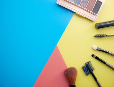 Makeup and makeup brushes, eye shadows on a colored background. Cosmetics for the face. With empty space on the left. View from aboveの写真素材