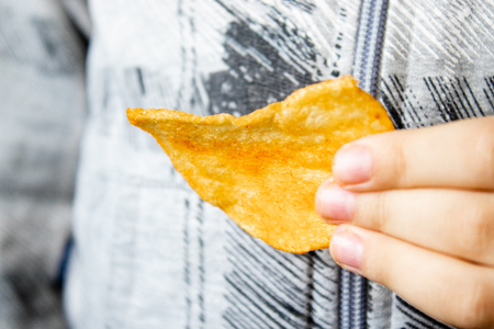 The child holds chips in his hand. Close-up. Junk food.の写真素材