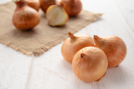 Burlap with yellow onions. Fresh onions on wooden background. Vegetables for a healthy diet. Vegan food.の写真素材