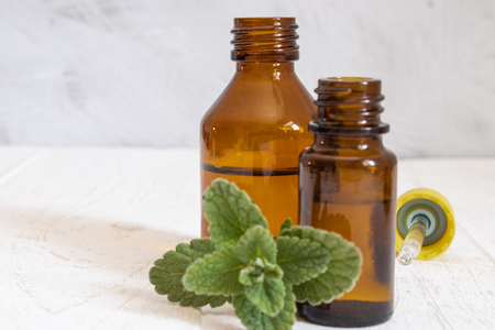 Natural essential oil of mint in a glass bottle with fresh mint leaves. Selective focus.の写真素材