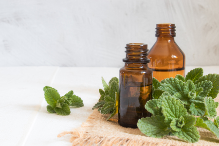 Organic essential oil of mint in a small glass jar with green leaves. Natural essential oil of mint.の写真素材