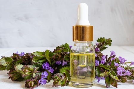 Fresh flowers and oil in a glass bottle on a wooden board. Natural essential oil.の写真素材