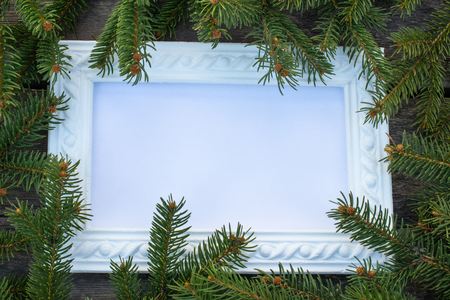 White frame and green branches of a Christmas tree on the background of old, wooden boards. Top view with copy space for your text.の写真素材