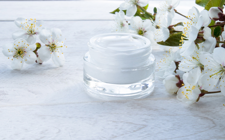 White can, cosmetic cream and cherry flowers on a white background. Face creamの写真素材