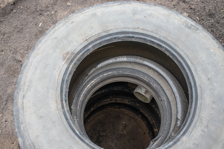 Sewer pit with car tires. Sewer system.の写真素材