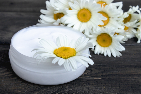 natural cosmetic cream near chamomile flowers on a wooden tableの写真素材