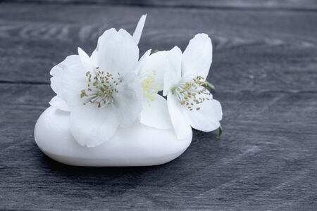 Cosmetic soap and white jasmine flowers with green leaves lie on a wooden background. There is a place for your text. Copy spaceの写真素材