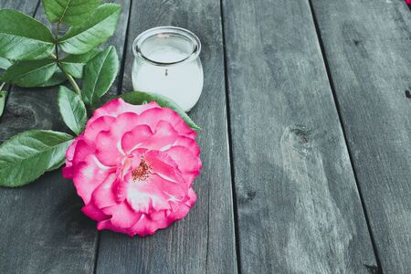 Rose and burning candle on an old wooden board. Flower frame. Pattern texture for design.の写真素材