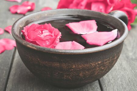 Tea from tea rose petals in a cup on a wooden rustic background. close-upの写真素材