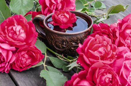 Tea from tea rose petals in a cup on a wooden rustic background. close-upの写真素材