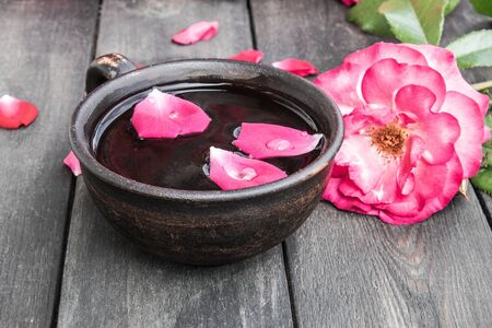 Tea from tea rose petals in a cup on a wooden rustic background. close-upの写真素材