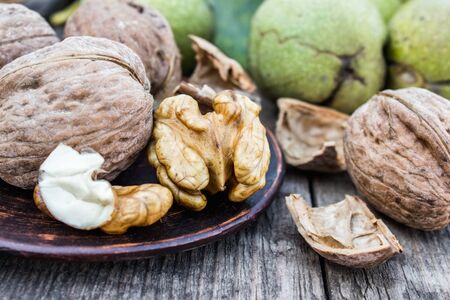 Walnuts and walnut kernels lie on a bowl on a rustic old wooden table. Walnut kernels. Harvest...